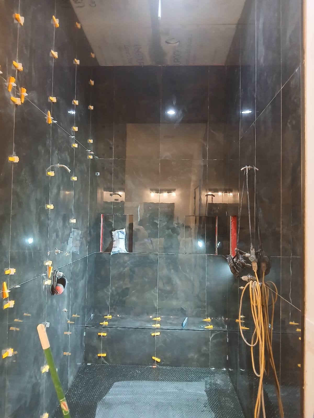 Dark marble shower installation with leveling clips in progress
