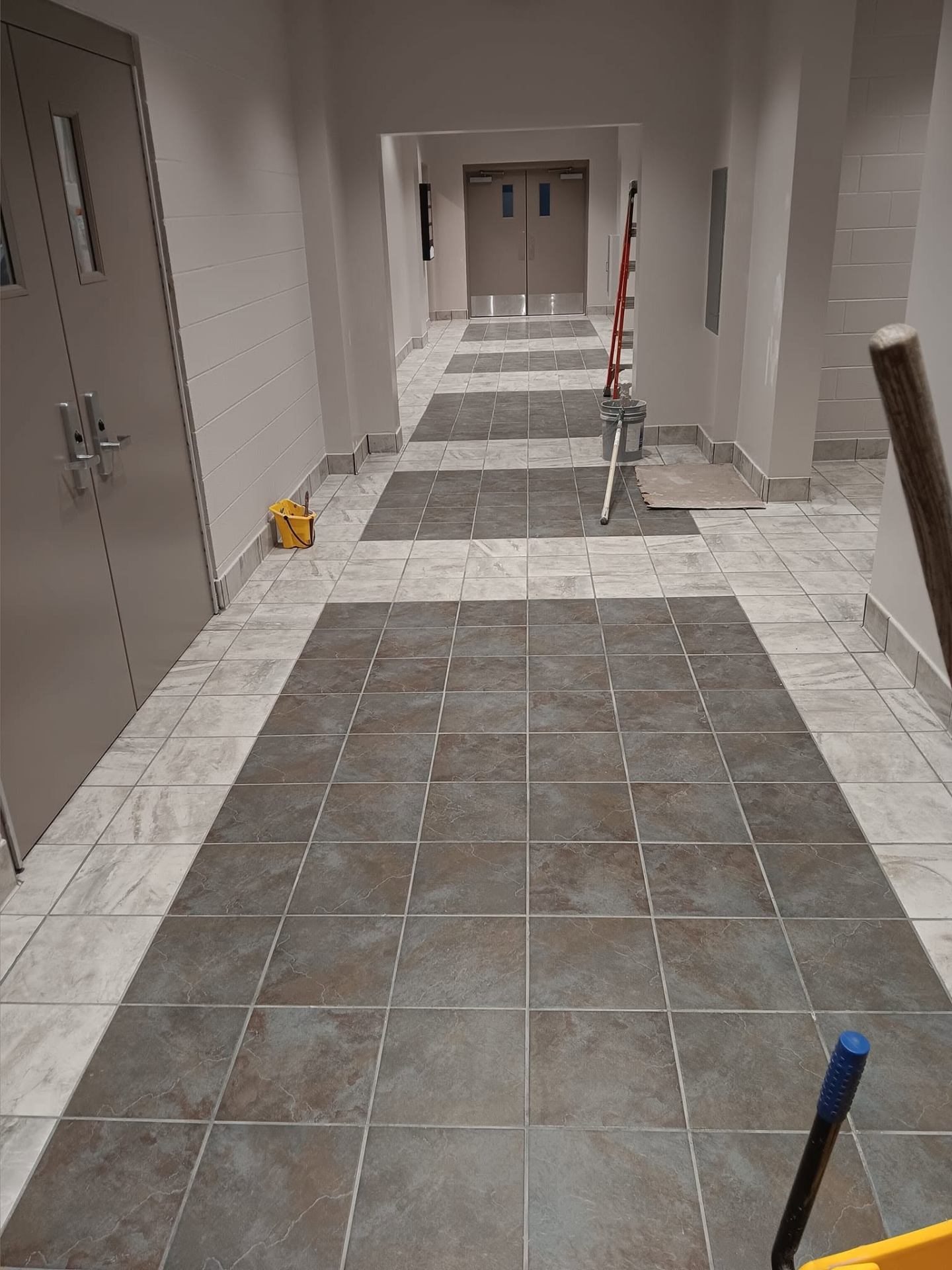 Long hallway with patterned grey and white tile floor