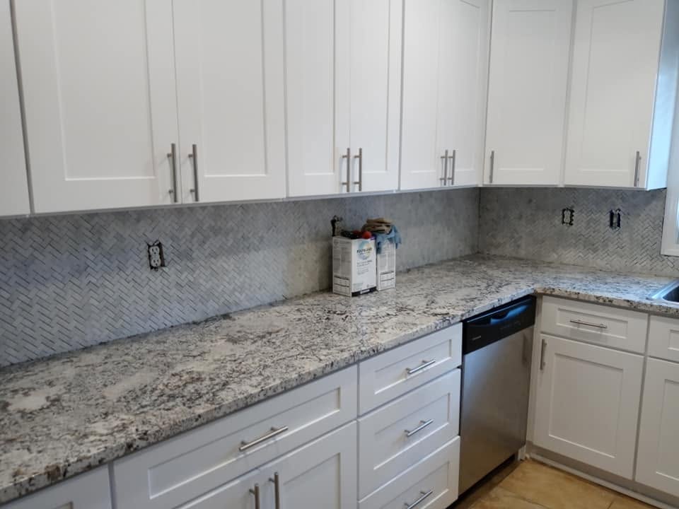 Herringbone marble mosaic backsplash on white shaker kitchen