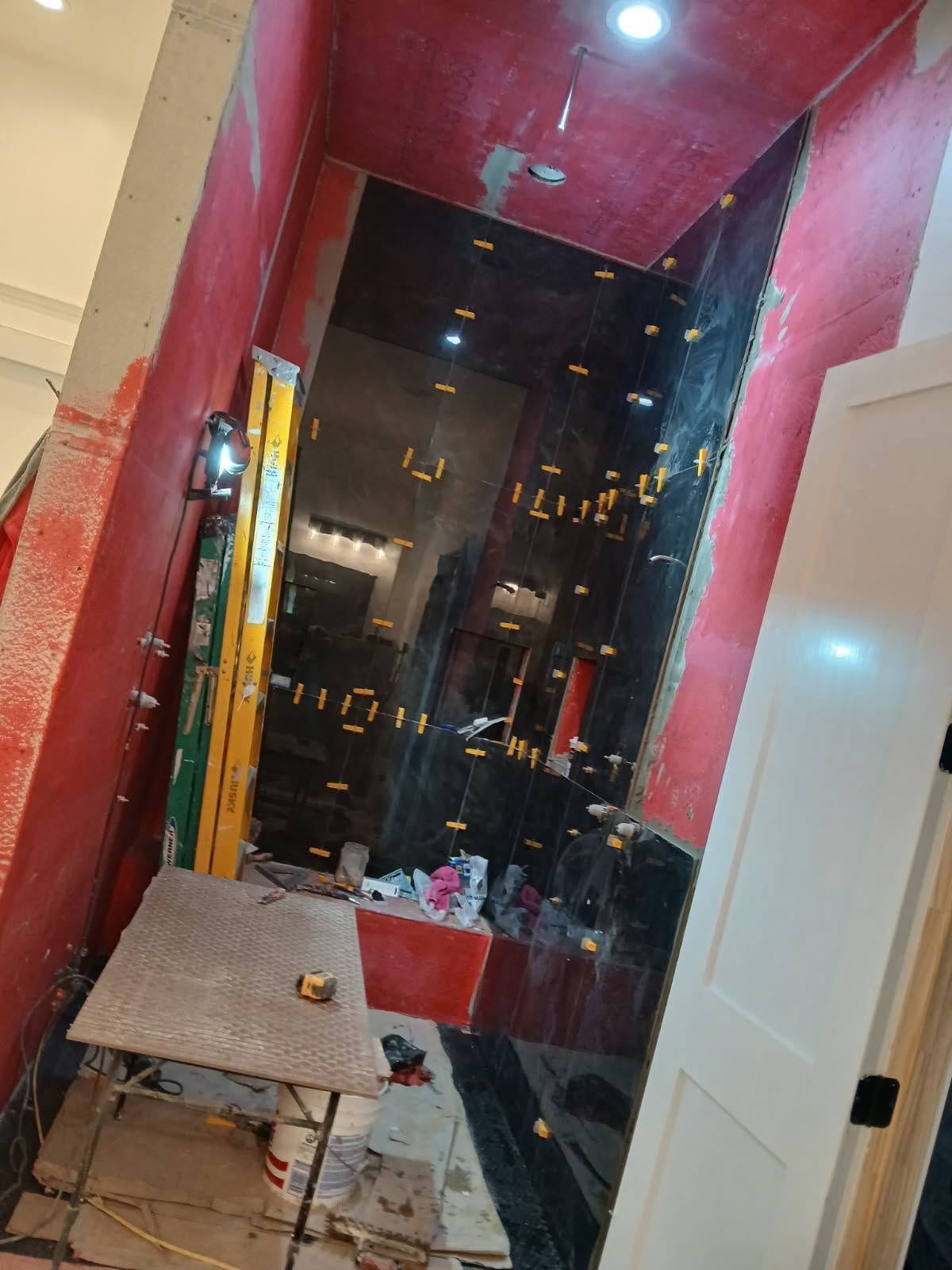 Black marble shower being installed with red waterproofing