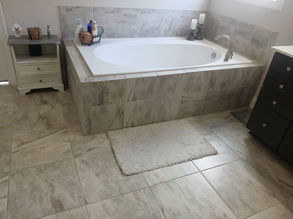 Grey travertine-look tile bathroom floor with soaking tub surround