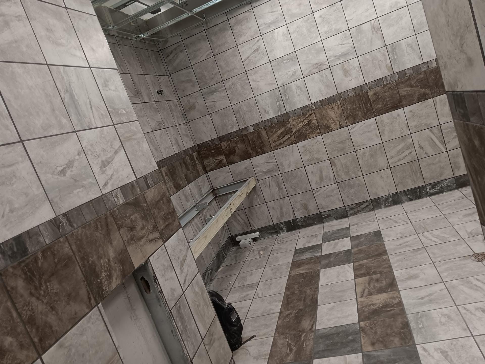 Tiled commercial bathroom walls with decorative brown stripe